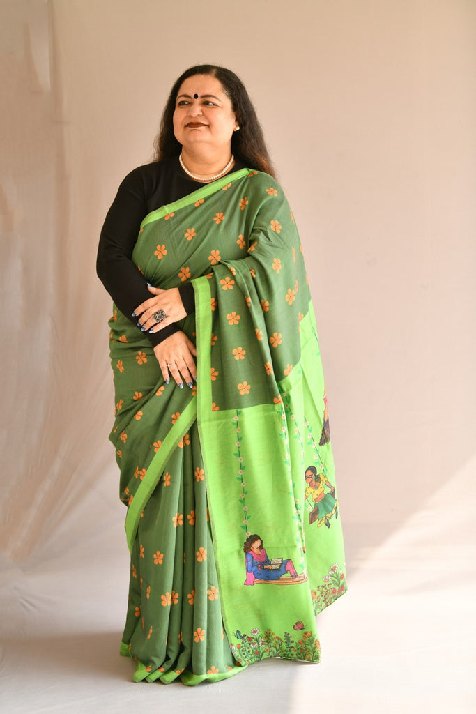 Dark green saree with orange flowers and light green patti border with printed flowers, meadow and women on swings, light and breezy printed sarees from House of Mirrah