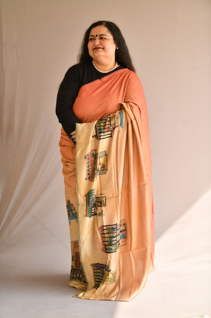 Front pose of a model wearing peach ombre Chanderi Silk saree with a running border of hand-painted and printed women at leisure in their balconies